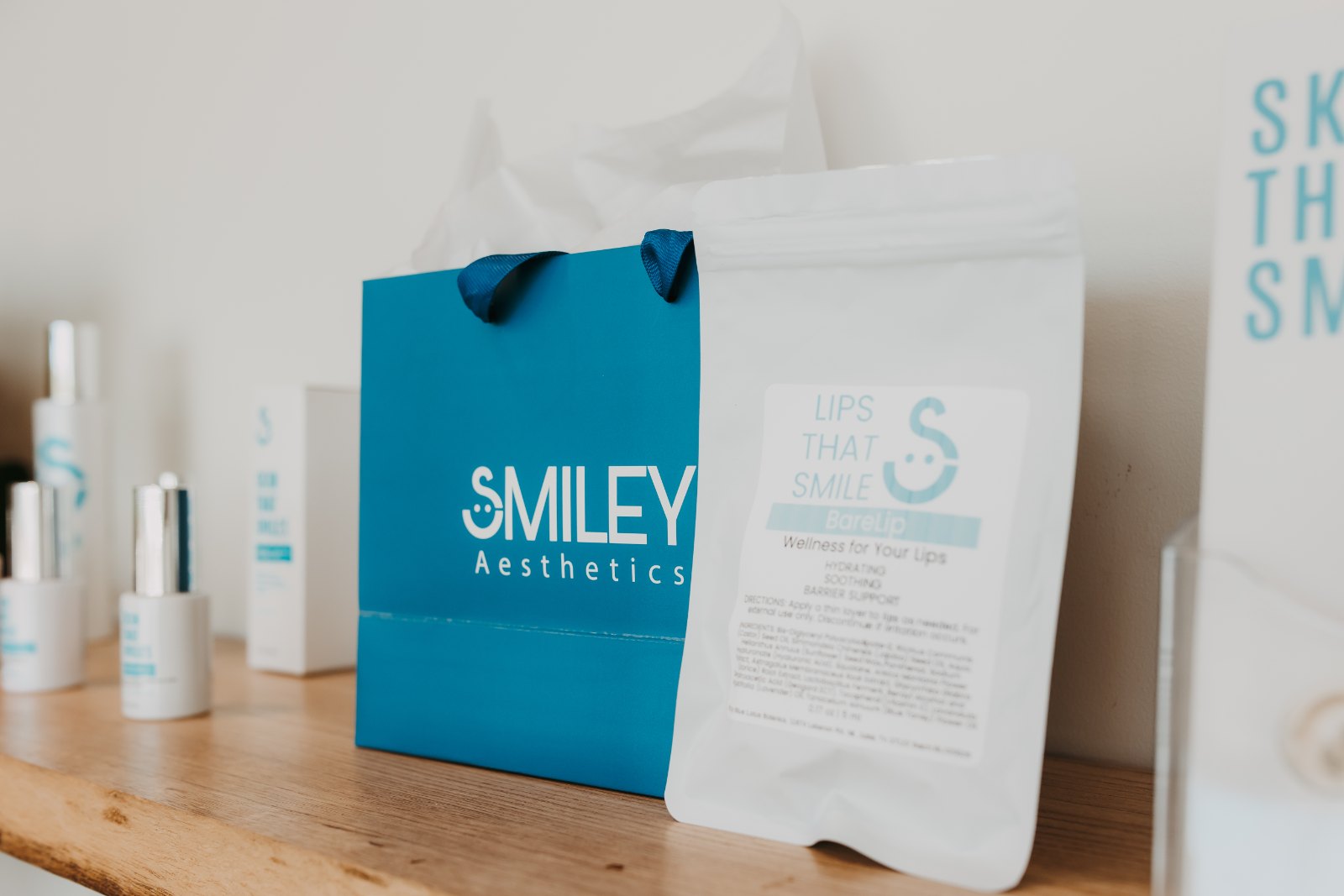A Smiley Aesthetics gift bag and skincare products on a wooden shelf